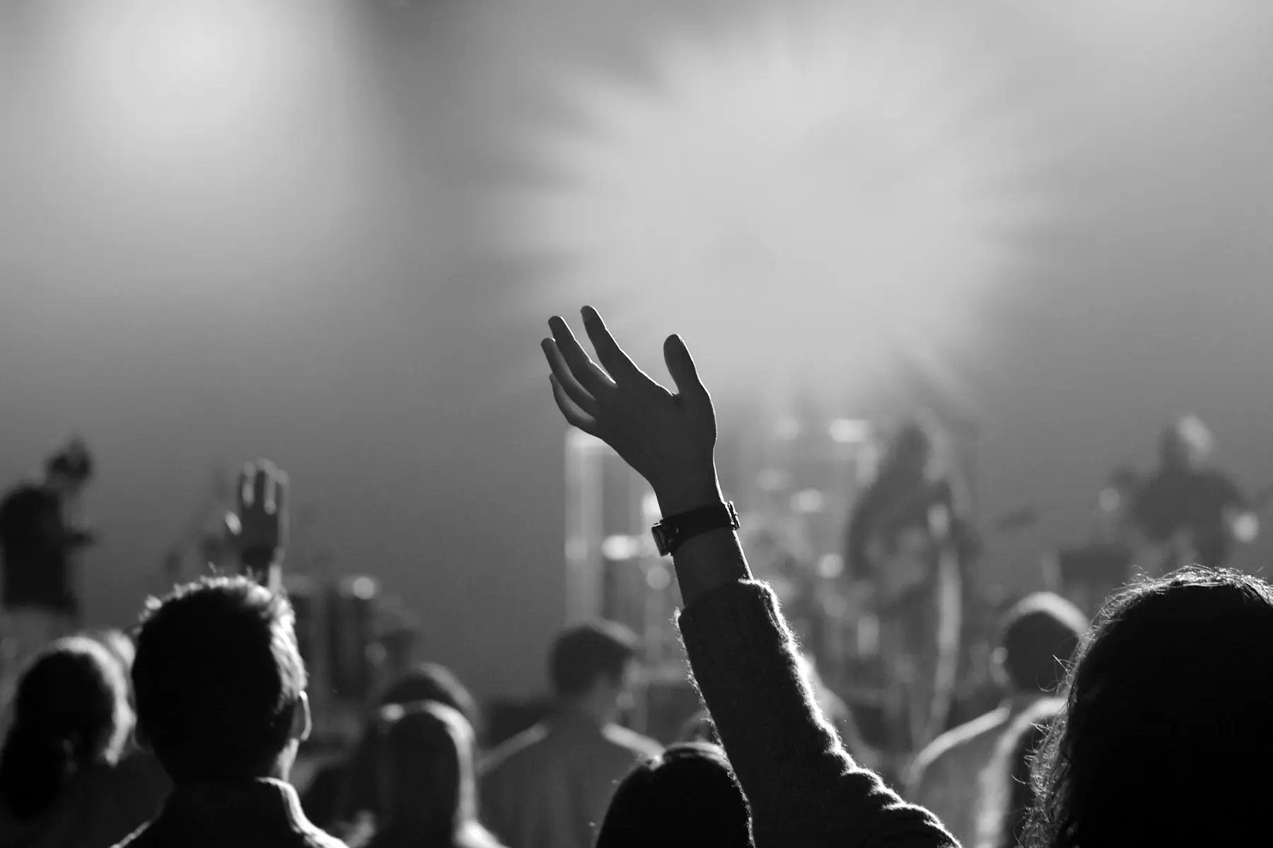 A raised hand in a worship gathering, in black and white.